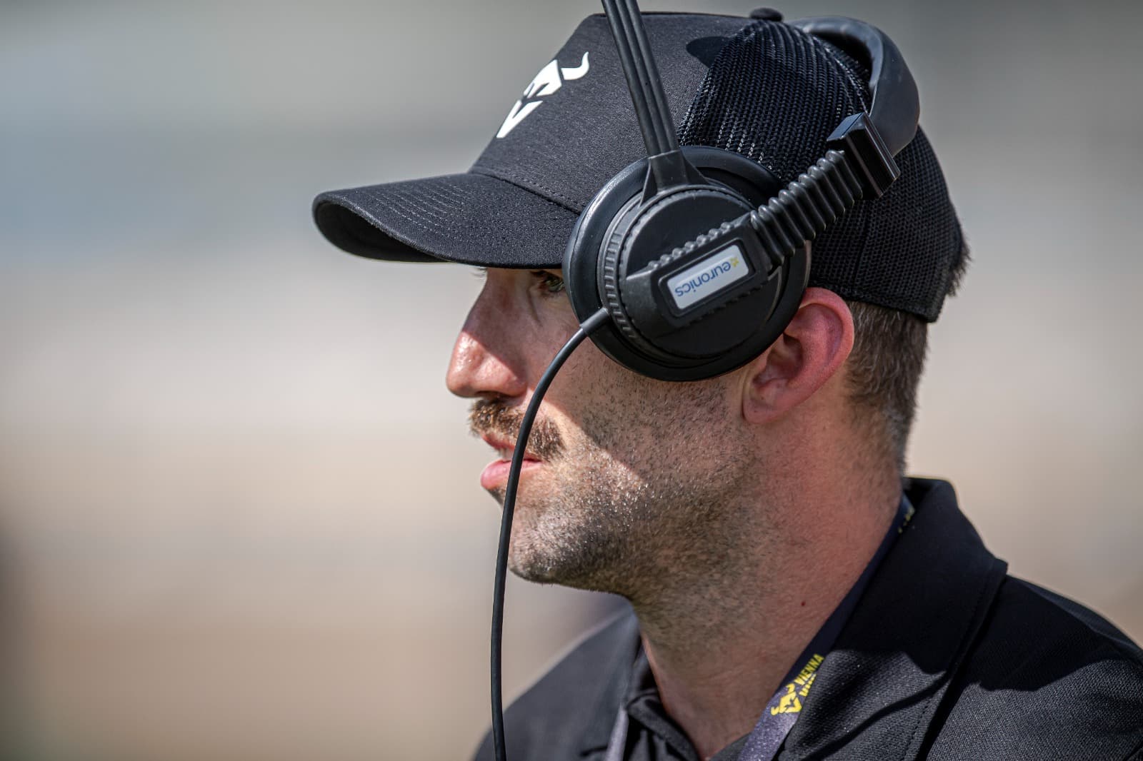 Close profile of Michael Gentilli in a headset on the Vienna sideline