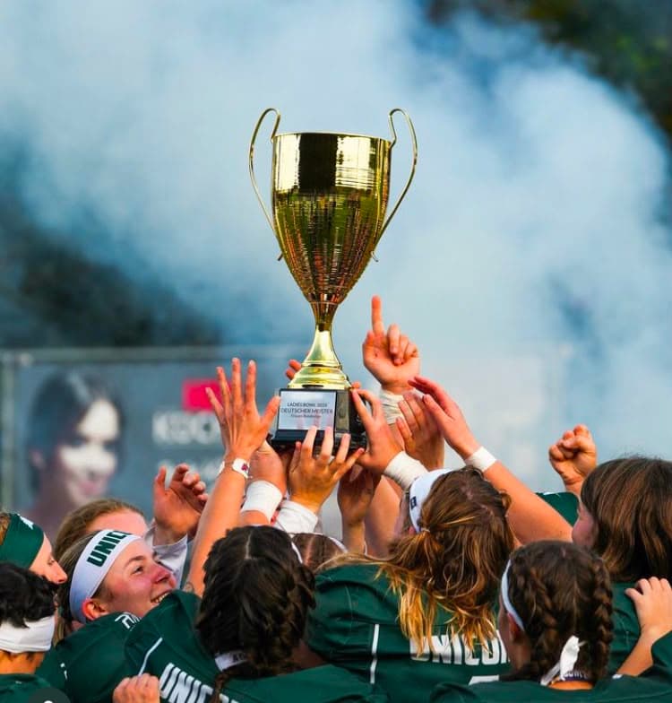 Players raising the Ladies Bowl trophy through the smoke